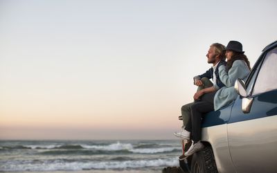 couple sitting on their car looking out over the ocean