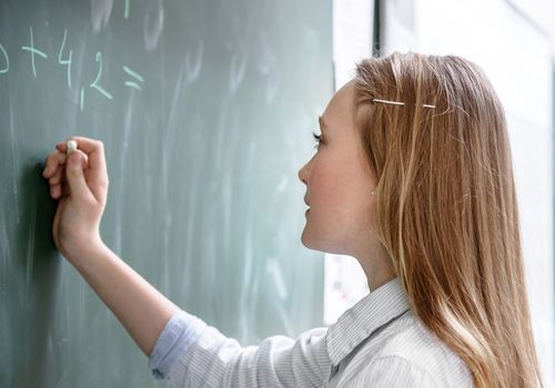 一个女学生在教室的黑板上做数学题