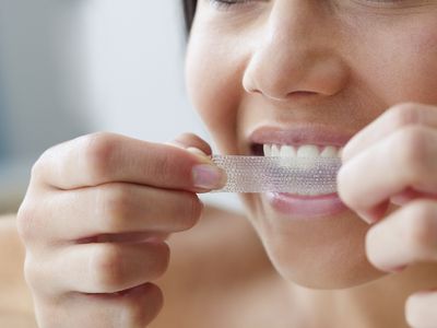 Woman putting on teeth whitening strip