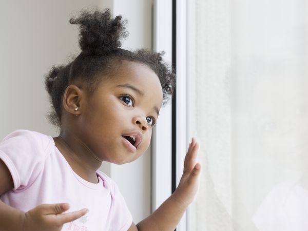 a Black baby girl looking out a window