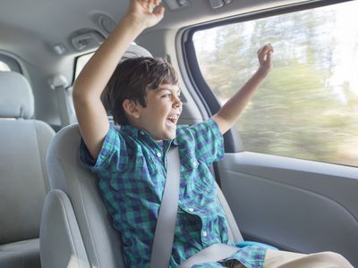 Enthusiastic boy cheering in back seat of car