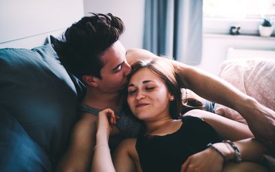 夫妻在床上，男人亲吻女人的头
