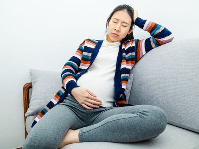 Pregnant woman with eyes closed sitting on the couch