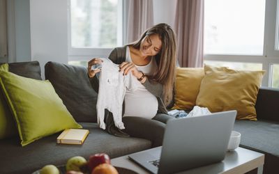 一位准妈妈在虚拟婴儿送礼会上向电脑展示她的婴儿服装