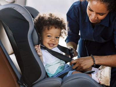 Mother buckling her baby into a car seat.