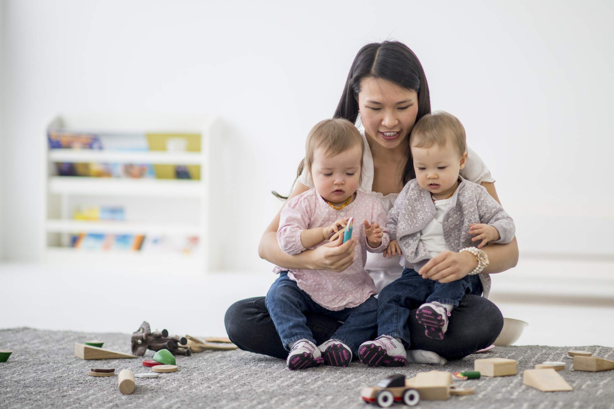 Daycare teacher playing with twin sisters.