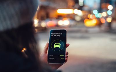 Woman requesting an Uber ride on an app on her smartphone.