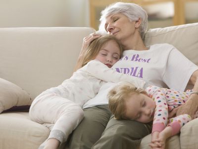 Caucasian grandmother and granddaughters napping on sofa together