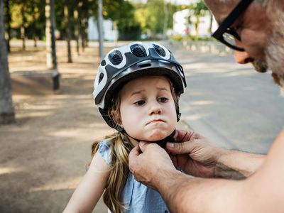 Grandpa putting helmet on granddaughter