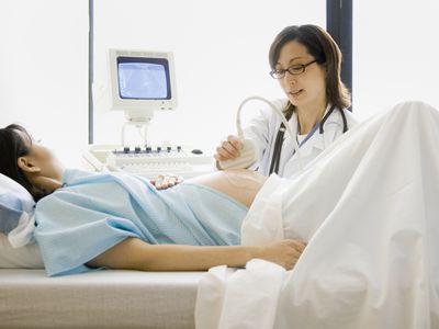 Doctor performing ultrasound scan on pregnant woman