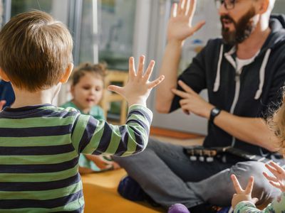 幼儿在幼儿园与老师和其他小朋友一起唱歌时举手示意