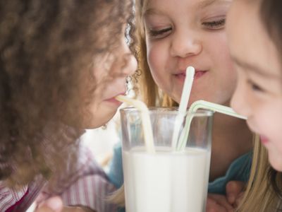 Girls sharing glass of milk