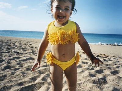 Smiling little girl in yellow swimsuit on a beach