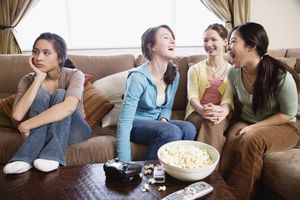 十几岁的女孩(14-15岁)坐在沙发上，三个女孩在说话，一个看着别处