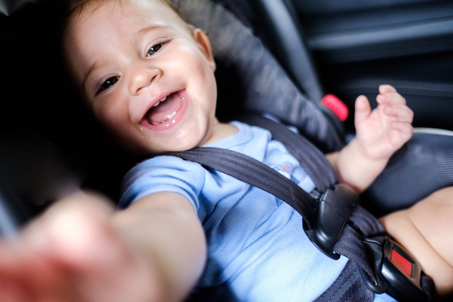 Baby boy smiling in car seat.