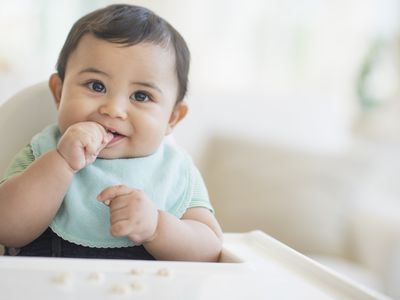 baby in high chair eating puffs