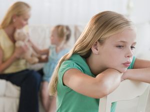 A sad girl with her mom and sister in the background