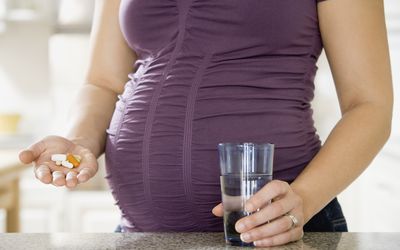 Pregnant African woman taking vitamins - stock photo