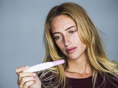 Young woman looking at pregnancy test with disappointed expression