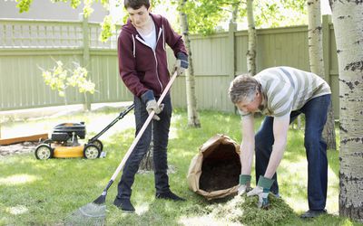 一个青少年和他们的爸爸在院子里干活。