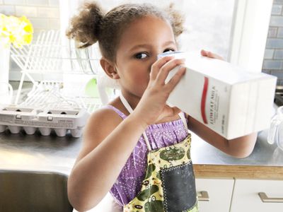 Young child drinking milk out of carton