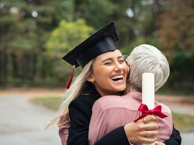 high school graduate hugging mom with diploma