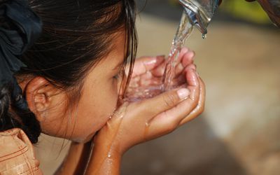 女孩喝着倒在她手里的水