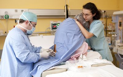 一位护士抱着一位分娩中的母亲，她正在接受硬膜外麻醉。