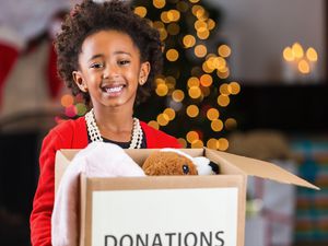 A tween holding a box of items to donate.