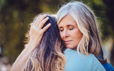 Grandmother lovingly embracing and holding teenage granddaughter