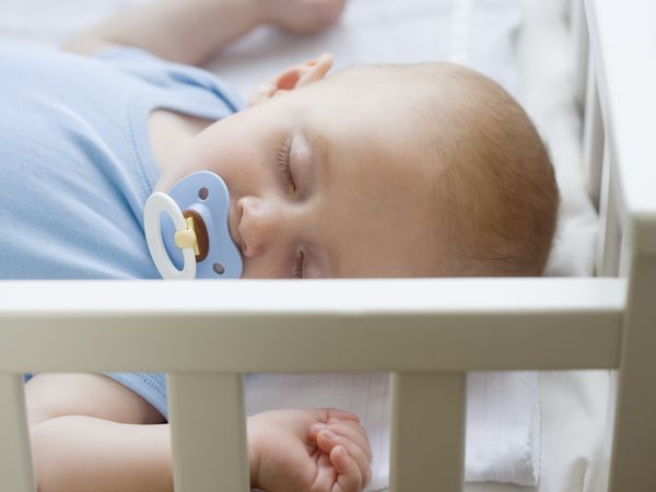 Baby sleeping in crib with pacifier