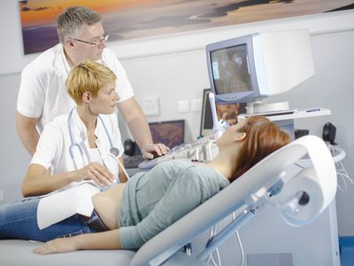 Ultrasound technicians examining pregnant woman