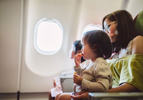 woman holding toddler on airplane