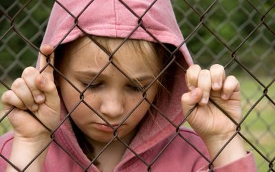 悲伤的女孩在篱笆旁