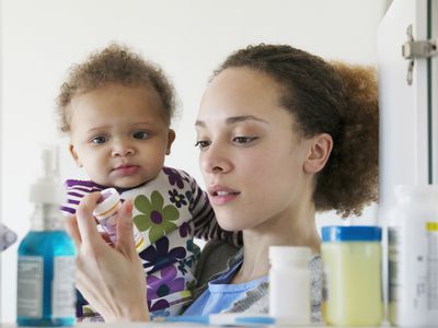 Black mother with baby reading pill bottle