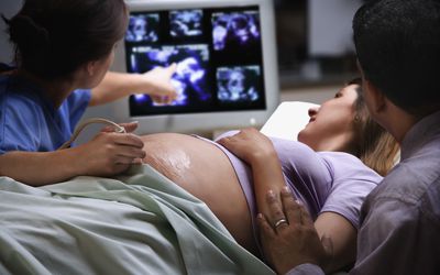女医生指着孕妇的超声波图