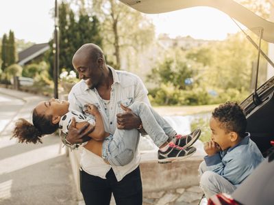 Man playing with kids behind car