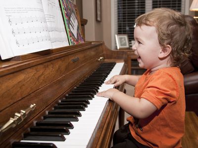 A toddler happily playing piano.