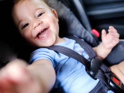 Baby boy smiling in car seat.