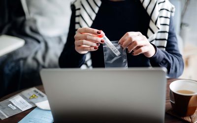 Cropped shot of young Asian woman consulting to her family doctor online in a virtual appointment, holding a medical test tub for at home STD testing