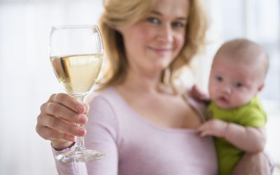 模特摆出一个抱着婴儿和一杯酒的母亲的姿势