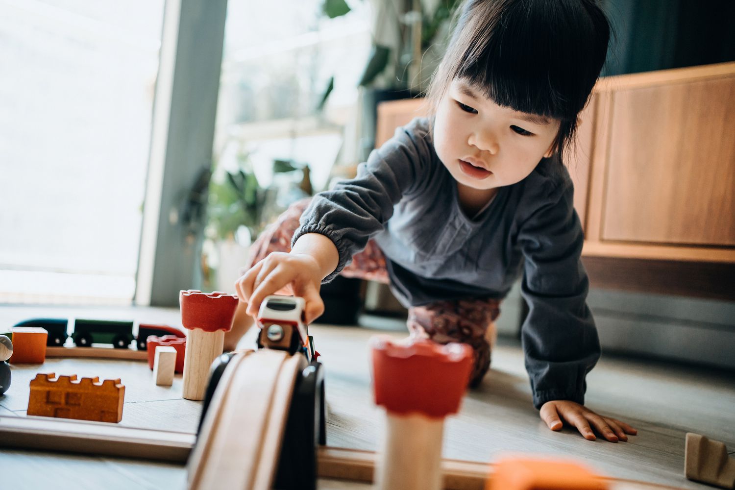 KiwiCo Review girl playing with wooden toy train in the living room at home