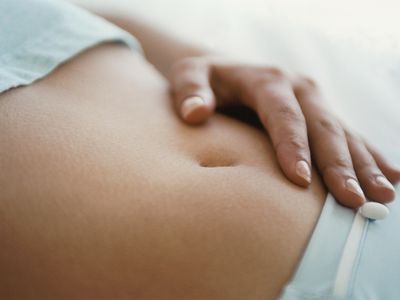 Hand on woman's abdomen, feeling bloated and sensitive due to superovulation