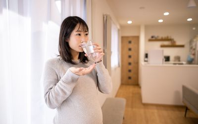 Pregnant woman taking medicine in living room