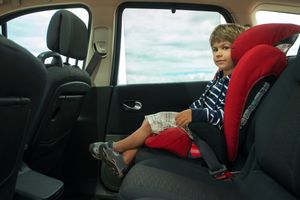 小男孩坐在高靠背助推器汽车座椅上，用安全带系紧。＂width=