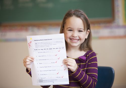 一个微笑的小女孩手里拿着一篇评分为a++的论文