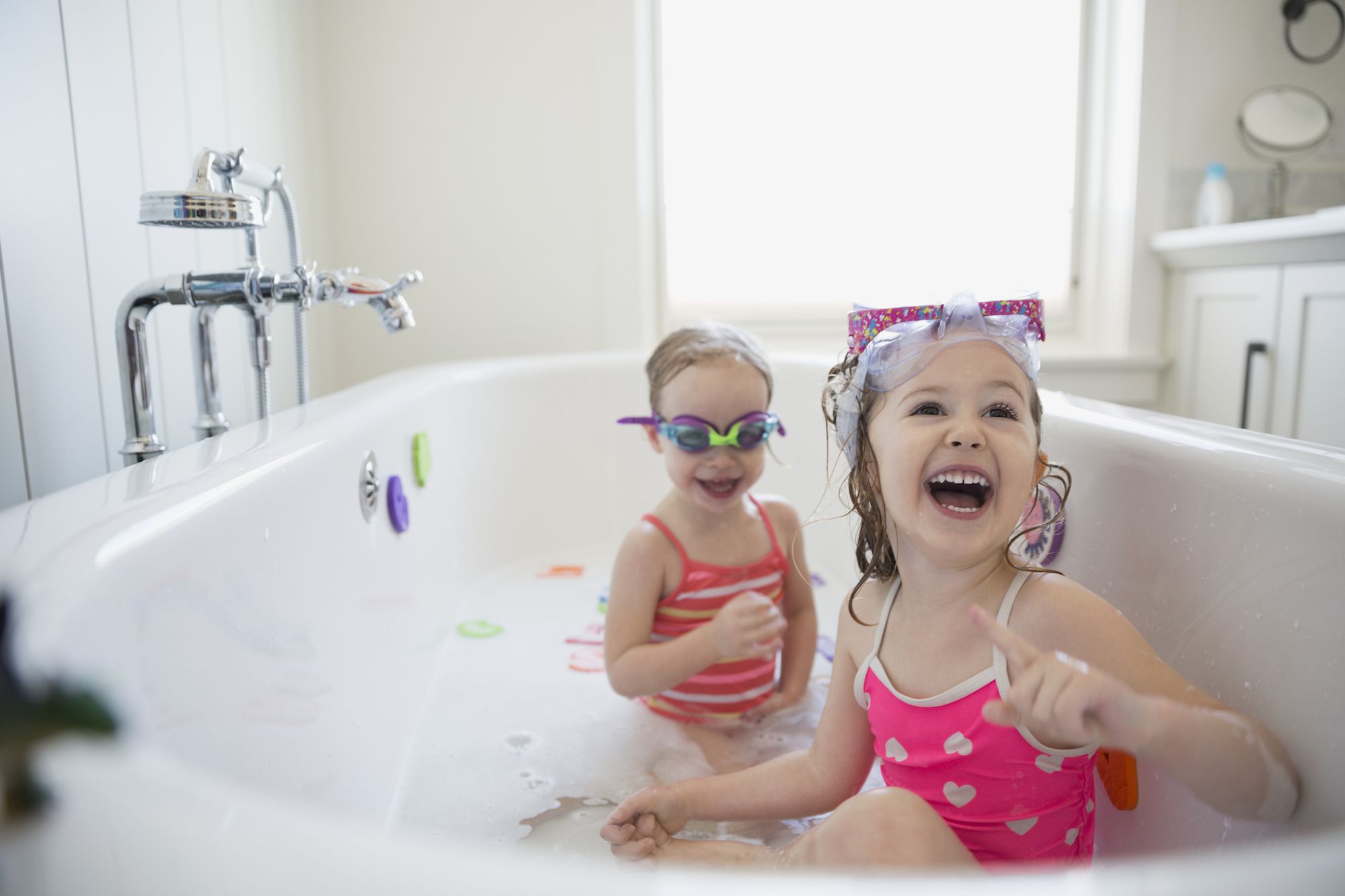 欢笑的姐妹在泡泡浴中玩耍