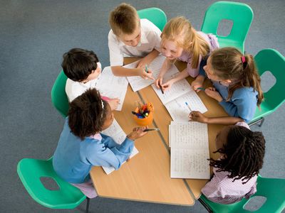 Elementary school children sitting around table, having discussion