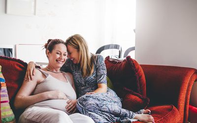 一对成熟的女同性恋伴侣，其中一方怀孕了，一起欢笑。