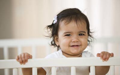 Baby girl standing up in a crib